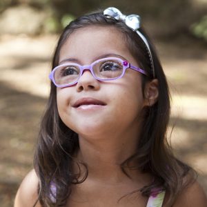 Garota com síndrome de Down e óculos ilustra a capa da Cartilha sobre Problemas de Visão.