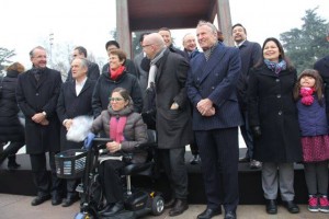 Celebração do Dia Internacional da Pessoa com Deficiência em Genebra. Várias pessoas, com e sem deficiência, estão posicionadas à frente do monumento da cadeira quebrada para durante a homenagem à data.
