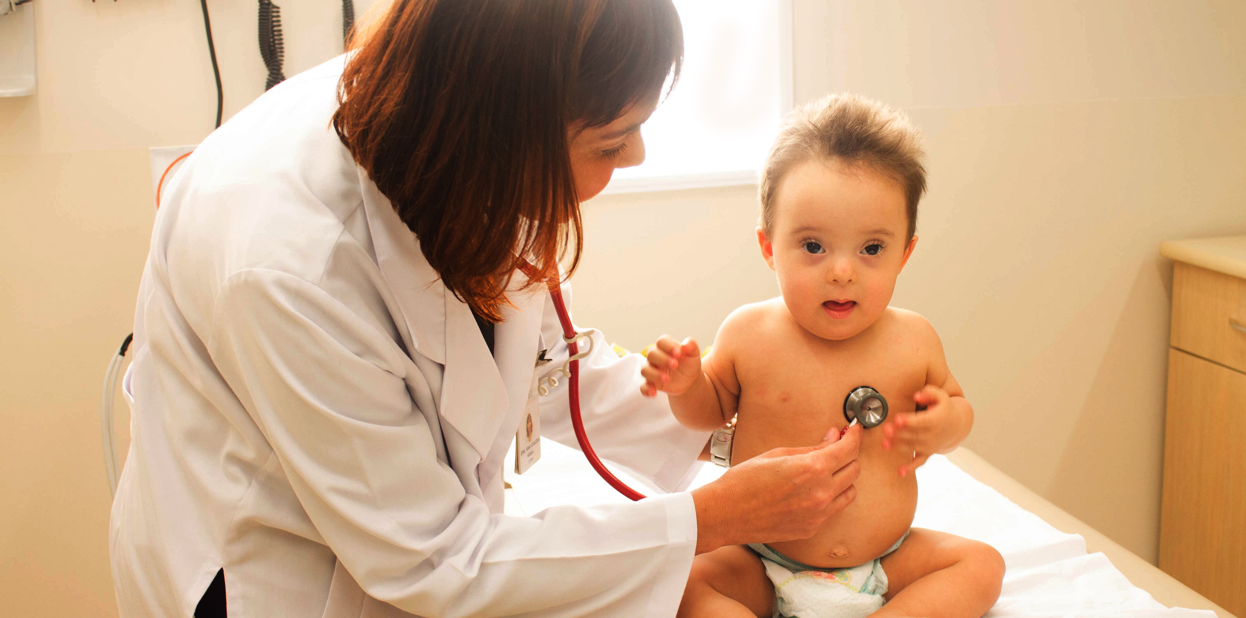 Uma médica pediatra examina um bebê com síndrome de Down.